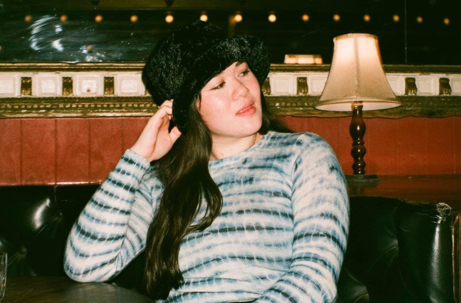 Woman sitting at a bar with a black fluffy hat on